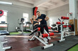 © RomanR - personal male trainer working with young slim woman client in gym