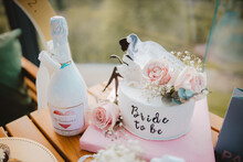 Closeup Of A Bottle Of Champagne And A Cake Decorated With Pink Roses For ''bride To Be'' Party