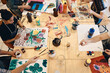 © Maskot - High angle view of students practicing painting at table in art class