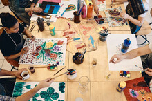 High Angle View Of Students Practicing Painting At Table In Art Class