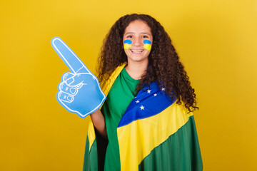 Brazilian, Caucasian, soccer fan girl with foam hand cheering for world cup, soccer fan, brazilian fan clothes.