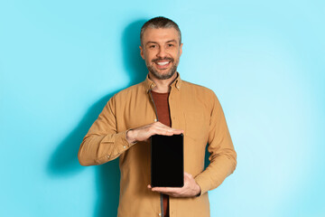 Poster - Male Holding Tablet Computer With Empty Screen On Blue Background
