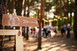 Wooden arrow sign with wedding rings on ceremony venue. Wedding party banner post . Direction info banner for guests in pine forest outdoors. Rustic or country style decor.