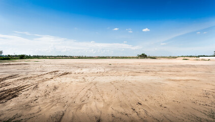 Empty dry cracked swamp reclamation soil, land plot for housing construction project with car tire print in rural area and beautiful blue sky with fresh air Land for sales landscape concept.