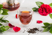 Hot black tea in a glass with double walls on a light background decorated with flowers
