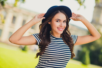 Sticker - Photo of shiny excited young lady wear striped dress arms headwear smiling walking enjoying sunny weather outdoors urban city park