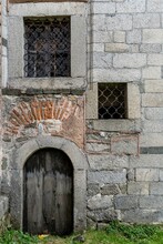 An Old Wooden Door To The Basement Of A Church And Two Windows With Metal Bars
