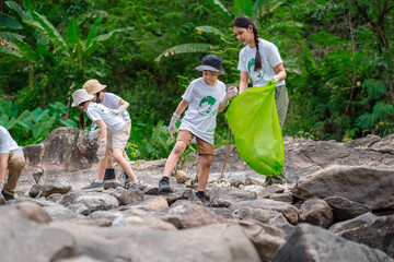 volunteer asian and children are collecting plastic bottles that flow through the stream into garbag