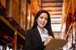 © winnievinzence - Portrait of Asian business woman or vice president smiling and holding clipboard at warehouse factory. Confidence people with positive vision working at import export company concept with copy space