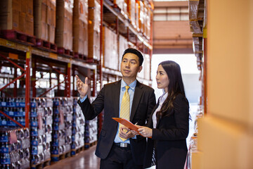 Asian two business people discussing of product at storage warehouse. manager explaining work to customer. checking goods logistic import and export.