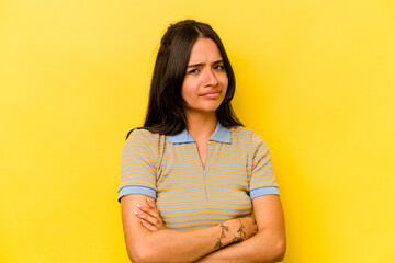 Wall Mural - Young hispanic woman isolated on yellow background suspicious, uncertain, examining you.