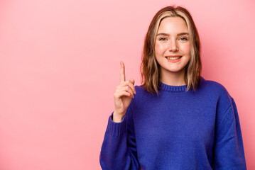 Young caucasian woman isolated on pink background showing number one with finger.