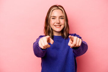 Wall Mural - Young caucasian woman isolated on pink background cheerful smiles pointing to front.