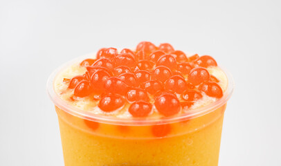 Sticker - Closeup of a cup of delicious orange bubble tea with boba on top of it on a white background