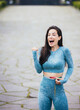 Image of shocked woman with wide open mouth in blue fitness wear with tape measure. Happy excited slim brunette girl measuring her waist size outside after training.