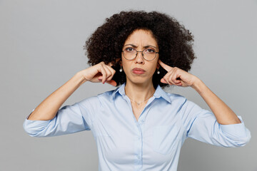 Wall Mural - Young employee business corporate lawyer woman of African American ethnicity in classic formal shirt work in office cover ears hands fingers do not want to listen scream isolated on grey background