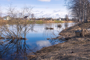 Verkhovye, Olonetsky district, Karelia, Russia, - April 28, 2022,, Narrow wooden pedestrian suspension bridge across the river in russian village near Olonets. Sunny summer evening.