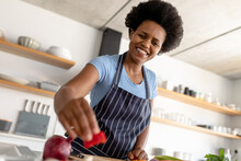 Smiling African American Mid Adult Woman Preparing Food In Kitchen At Home