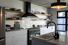 Interior Of Modern Kitchen With Illuminated Pendant Lights Over Sink At Kitchen Island