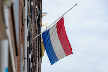 04 May every year, Remembrance of the Dead (Nationale Dodenherdenking) National flag of the Netherlands with half-mast, Memorial to victims of the world war two, Dutch flag hanging outside building.