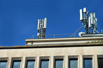 Canvas Print - Telecommunications antennas placed on the roof of a building against a blue sky on a sunny day