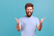 © khosrork - Portrait of bearded man approves incredible promo keeps thumbs up likes and agrees being satisfied with something, winking to camera. Indoor studio shot isolated on blue background.