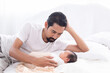 Asian young father looking newborn while baby deeply sleeping with happiness. Little infant wrapped in thin white cloth with happy and safe. Dad and toddler spend time together.