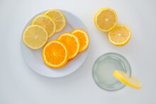 Top View Of Slices Of Lemon And Orange, On A Plate And Glass, White Background