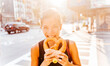 Woman eating pretzel in Manhattan, a classic New York City snack. Multiracial asian young professional portrait smiling at camera