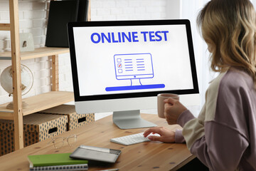 Woman taking online test on computer at desk indoors