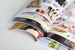 © New Africa - Many open magazines on white wooden table, above view