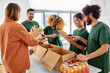 © Syda Productions - charity, donation and volunteering concept - happy smiling male volunteer with clipboard and woman taking box of food at distribution or refugee assistance center