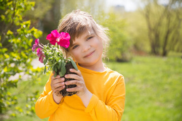 Wall Mural - Spring awakening. Slow life. Enjoying the little things. Dreaming of spring. child with flowers in the garden. Child girl plant flowers in the garden near the houme on spring day.