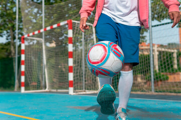 Wall Mural - Image of a man kicking the ball with his foot. Close-up image of a young boy hitting the ball with his feet on a blue soccer field with the goal in the background.