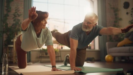 Wall Mural - Happy Middle Aged Couple Doing Gymnastics and Yoga Stretching Exercises Together at Home on Sunny Morning. Concept of Healthy Lifestyle, Fitness, Recreation, Couple Goals, Wellbeing and Retirement.