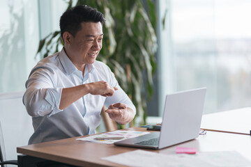 Wall Mural - Asian businessman communicating in video call with deaf client at her workplace in modern office