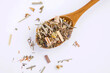 Wooden spoon with dry herbal tea on a white isolated background, top view