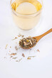 Wooden spoon with dry herbal tea and glass cup of tea on a white isolated background.