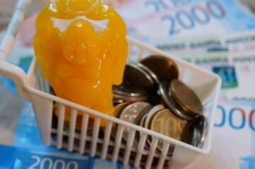 A Buddha figure in a basket with coins. A symbol that attracts financial luck.