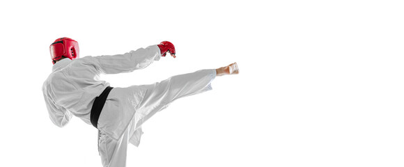 Back view. Portrait of young sportive man wearing white dobok, helmet and gloves practicing isolated over white background. Concept of sport, workout, health.