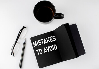 Poster - MISTAKES TO AVOID written text in small black notebook with coffee , pen and glasess on white background. Black-white style
