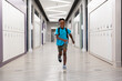 Full length of smiling african american elementary schoolboy running in corridor at school