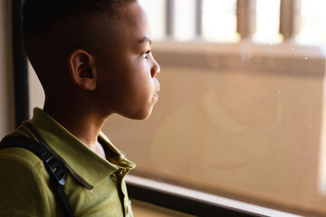 Close-up of thoughtful african american elementary schoolboy looking through window in classroom