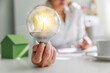 Businesswoman's hand holding a lightbulb on desk. Ideas, innovation inspiration concept