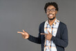 © Svyatoslav Lypynskyy - Smiling black young man in glasses pointing with hands sideways looking at camera. Cheerful african american young man in plaid shirt looking at camera isolated on gray background