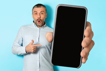Poster - Shocked Middle Aged Male Showing Mobile Phone Screen, Blue Background