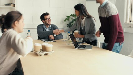 Aufkleber - A businesswoman brings her coworkers cups of coffee. A diverse happy group of businesspeople greeting each other with handshakes and drinking tea during a meeting. Colleagues talking in a meeting