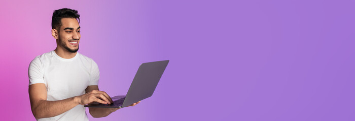Poster - Smiling young Arab man working on laptop, having video call, chatting online in neon light, banner design with free space