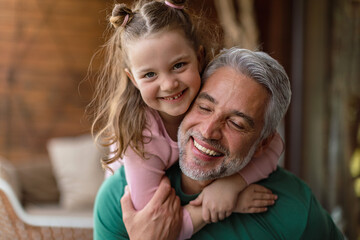 Wall Mural - Portrait of little cute daughter hugging her happy father at home.