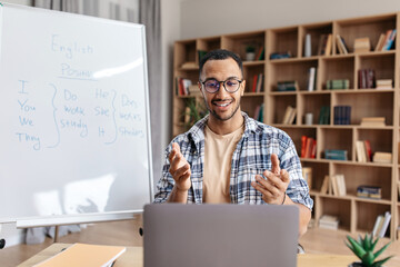 Poster - Happy professional male teacher having videocall, explaining new theme to students via laptop, sitting at desk